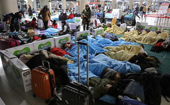 제주공항 이용객들이 지난 12일 공항 바닥에 깔린 매트리스 위에서 자거나 쉬고 있다. [연합뉴스]