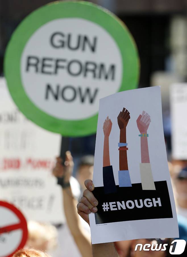 17일(현지시간) 플로리다주(州)에서 열린 총기규제 지지 집회에서 한 시민이 '충분하다'고 적힌 팻말을 들고 있다.© AFP=뉴스1