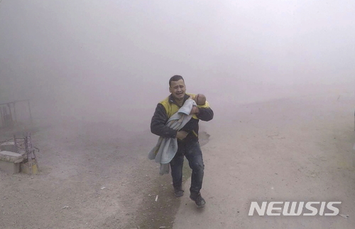 【다마스쿠스=AP/뉴시스】시리아 다마스쿠스 인근 반군 점령지역에서 6일(현지시간) 정부군의 공습이 이어지고 있는 가운데 한 구조대원이 울면서 어린 아이를 안고 뛰어가고 있다. 사진은 시리아민방위대(SCD)가 제공했다. 2018.2.21.