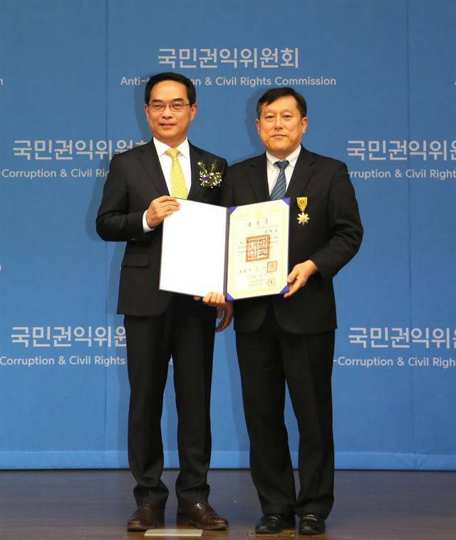 27일 정부세종컨벤션에서 열린 '국민권익의날 기념식'에서 '현대차 차량 결함' 공익제보로 국민훈장을 수훈한 김광호(오른쪽)씨. 왼쪽은 권태성 국민권익위원회 부위원장 겸 사무처장. 국민권익위 제공