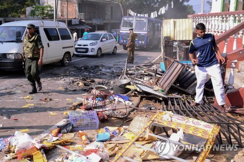 6일 스리랑카 중부 캔디 지역에서 종교간 충돌로 상점들이 부서진 가운데 경찰이 지나가고 있다.[AFP=연합뉴스 자료사진]
