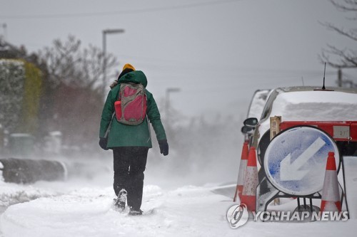 영국 맨체스터에서 눈 덮인 길을 걷고 있는 한 여성 [AFP=연합뉴스]