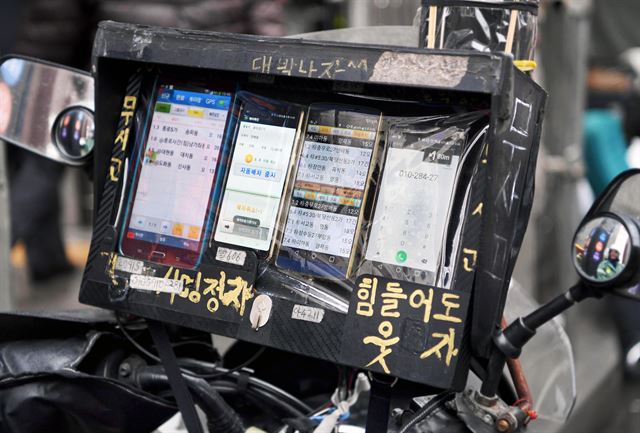 오토바이 배송기사 김동용씨는 고단한 삶 속에서도 웃음을 잃지 않으려는 다짐으로 콜 수신용 PDA 거치대에 ‘힘들어도 웃자’ ‘무사고’ 등의 문구를 적었다.