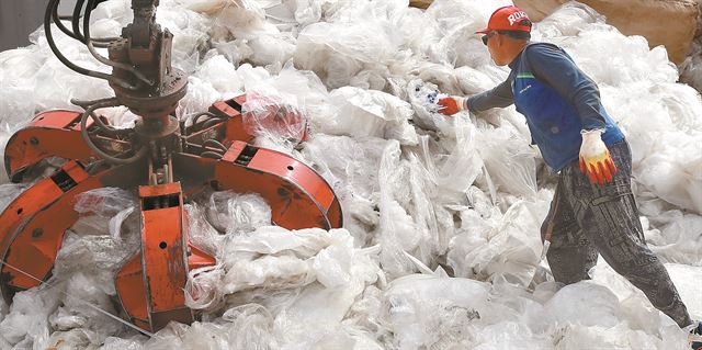 서울과 경기 고양시의 경계에 있는 한 폐비닐 재활용업체에서 한 노동자가 비닐 압축을 준비하고 있다. 연합뉴스