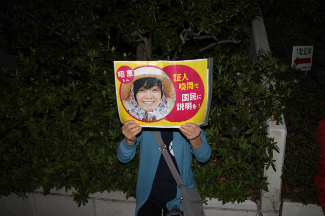 6일 저녁 도쿄 치요다구 일본 총리 관저 앞 시위에서 한 참가자가 아베 총리 부인 아키에씨의 국회 증인 소환을 요구하는 손팻말을 들고 있다. ⓒ김경년