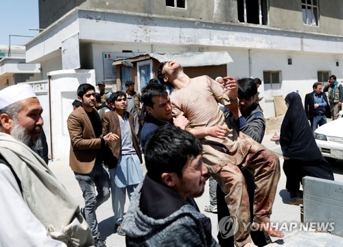 22일 아프간 수도 카불의 유권자 등록센터 밖에서 자폭테러가 벌어진 가운데 주민이 부상자를 옮기고 있다.[로이터=연합뉴스 자료사진]
