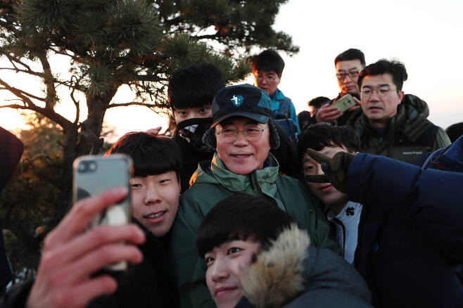 1월 1일 2017년을 빛낸 의인 6명과 북한산 산행에 나선 문재인대통령이 사모바위에서 새해 첫 일출을 배경으로 기념촬영을 하고 있다. [사진 청와대]