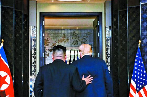 김정은 북한 국무위원장(왼쪽)과 도널드 트럼프 미국 대통령이 12일(현지시간) 싱가포르의 카펠라 호텔에서 북·미 정상회담 공동성명 문서에 서명을 마치고 이동하고 있다. [신화=연합뉴스]