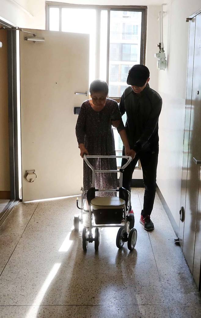 김영각(71)씨가 담관암·뇌졸중을 앓는 부인(70)을 부축해 집 앞 복도에서 함께 걷고 있다. [김상선 기자]