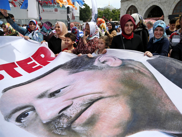 터키 대선(24일)을 앞두고 레제프 타이이프 에르도안 대통령의 지지자들이 18일 대통령 얼굴이 인쇄된 대형 현수막을 들고 이스탄불 거리를 행진하고 있다. 이스탄불=AP 뉴시스