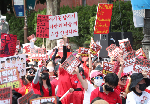 붉은 옷을 입은 여성들이 지난 7일 오후 서울 대학로 일대에서 열린 ‘불법촬영 편파수사 3차 규탄 시위’에 참가해 ‘여성유죄 남성무죄 성차별 수사를 중단하라!’ 등이 적힌 피켓들을 높이 들어보이고 있다. 뉴스1