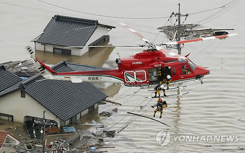 일본 폭우 피해 속출 [교도=연합뉴스 자료사진] 지난 7일 오카야마현 구라시키의 물에 잠긴 주택가에서 한 주민이 헬기에 구조된 모습.
