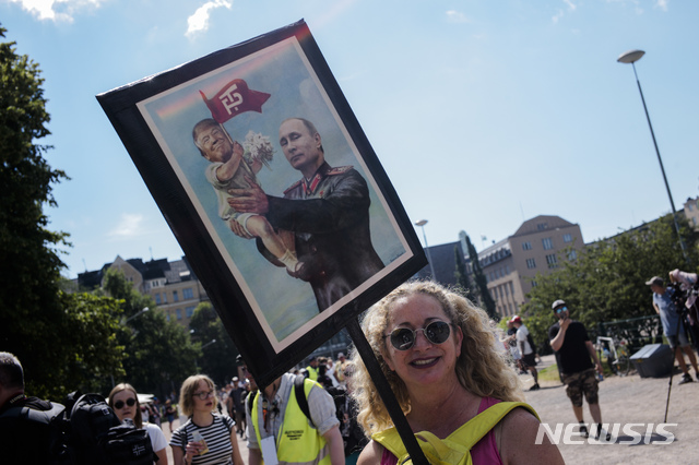 【헬싱키=AP/뉴시스】한 여성이 15일(현지시간) 핀란드의 수도 헬싱키에서 도널드 트럼프 미국 대통령과 블라디미르 푸틴 러시아 대통령의 정상회담 반대 시위에 참석하고 있다. 2018.07.16