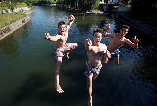 슬로베니아의 수도 류블랴나에서 습하고 더운 날씨를 보이고 있는 19일(현지시간)  청년들이 더위를 식히기 위해 류블랴나 강으로 뛰어들고 있다.  로이터 연합뉴스