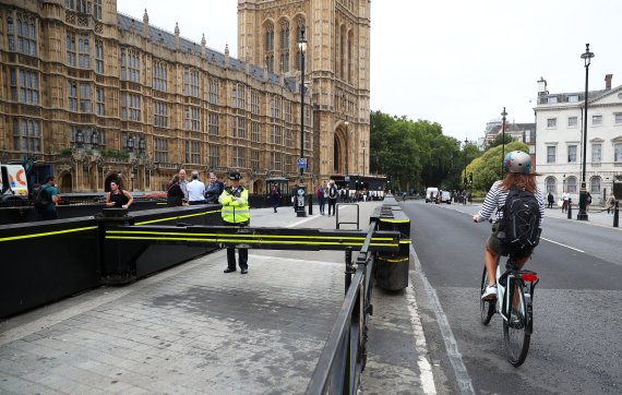 영국 런던의 의회 옆 도로에서 15일(현지시간) 한 시민이 자전거를 타고 경관 옆을 지나고 있다.로이터연합뉴스