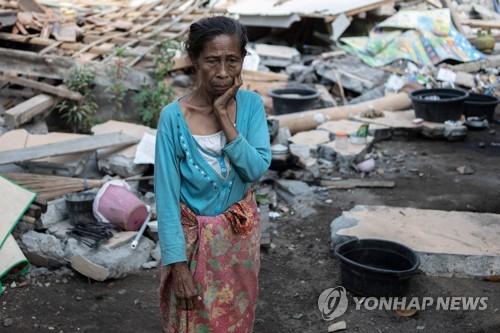 2018년 8월 22일 인도네시아 롬복 섬 라부 판단 마을의 무너진 집 앞에서 어두운 표정을 하고 있는 현지 주민. [AFP=연합뉴스자료사진]