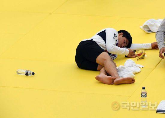 안창림 선수가 유도 훈련장에 힘없이 누워 핸드폰을 만지고 있다.