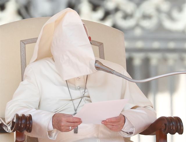 프란치스코 교황이 9월5일 바티칸 성베드로광장에서 연설하던 도중 바람에 날린 망토에 얼굴을 가리고 있다. 로이터 연합뉴스