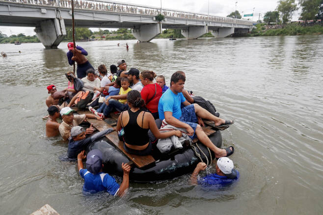 온두라스 이민자들이 멕시코 국경을 넘기 위해 수치아떼 강을 튜브를 이용한 배로 넘고 있다. EPA=연합뉴스