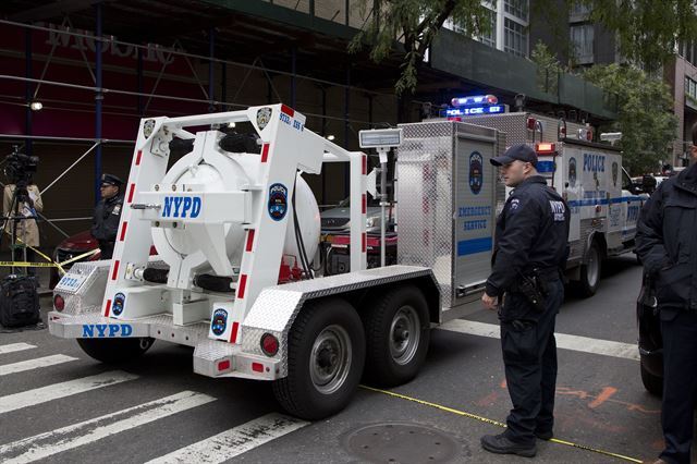 26일 미국 뉴욕 경찰이 맨해튼에서 발견된 폭탄으로 의심되는 소포를 완전봉인차량에 싣고 트럭으로 이동하고 있다. 뉴욕=AP 연합뉴스