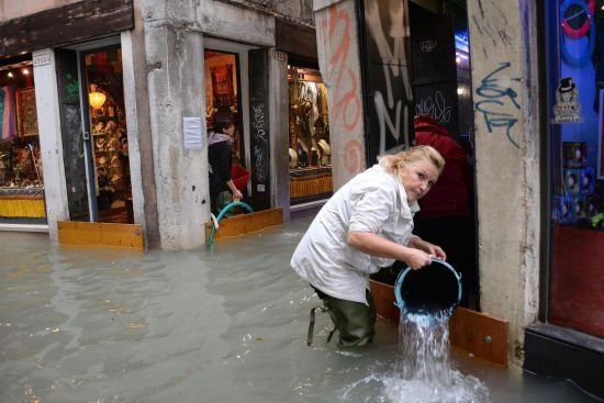 베네치아의 한 상점 주인이 건물에 범람한 물을 퍼내고 있다. [AP 뉴시스]