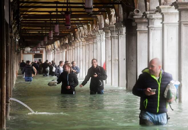 29일(현지시간) 폭우와 홍수를 피해 이탈리아 베네치아 산마르코 광장 옆 아치를 걷는 관광객들의 모습/AFPBBNews=뉴스1