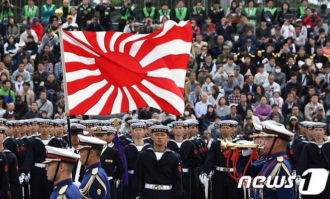 지난 10월14일 일본 사이타마현 아사카 육상자위대 훈련장에서 열린 자위대 사열식에 참가한 해상자위대원들이 욱일 문양의 그려진 자위함기 아래 서 있다. © AFP=뉴스1
