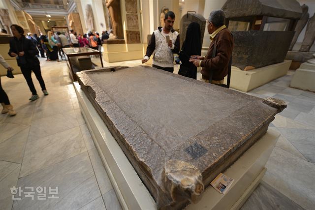 관람객들이 이집트박물관 1층에서 파라오의 미라를 제작한 석판을 보며 얘기를 나누고 있다. 끝부분에 피가 빠지는 구멍이 있다.