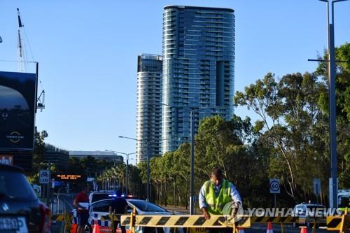 24일 호주 시드니의 올림픽파크에 있는 오팔 타워(배경 건물)가 붕괴 위험이 있는 것으로 알려져 주민들이 대피했다. 관계자가 오팔 타워로 가는 도로를 차단하고 있다. [EPA=연합뉴스]
