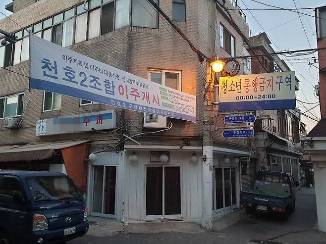 24일 서울 강동구 천호동의 한 골목에 '청소년 통행금지 구역' 알림판과 '재건축을 위한 이주개시' 플래카드가 함께 걸려 있다. 이가영 기자