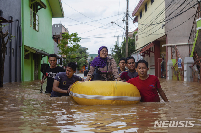 【마카사르=AP/뉴시스】23일(현지시간) 인도네시아 남술라웨시 마카사르에 홍수가 나 한 여성이 고무보트를 타고 주민들의 도움으로 대피하고 있다. 이번 폭우로 댐이 넘치고 산사태가 발생해 최소 6명이 숨지고 2000명 이상의 이재민이 발생했다고 현지 관계자가 밝혔다. 2019.01.23.