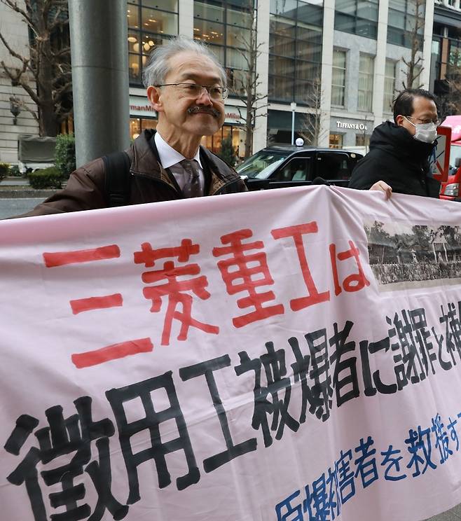 아다치 슈이치 변호사가 2월15일 일본 도쿄 미쓰비시중공업 본사 앞에서 강제징용 피해자에게 사죄하라는 펼침막을 들고 있다(왼쪽). 류우종 기자