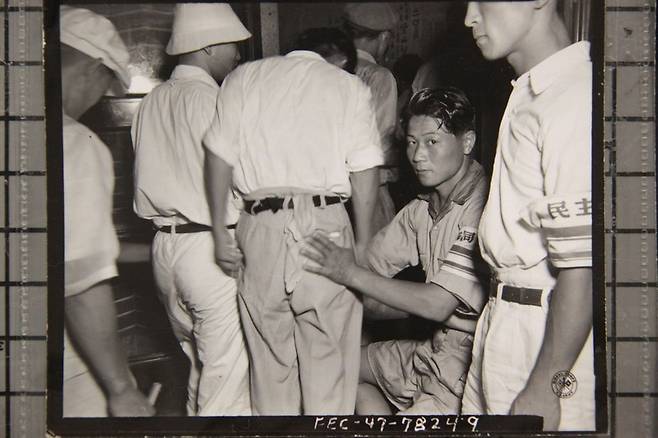 1947년 8월15일 도쿄에서 열린 재일조선인들의 광복 2주년 기념식에 참석한 사람들이 입장 전 몸 수색을 받고 있다. 미국국립문서관 원본, 국사편찬위원회 보관자료