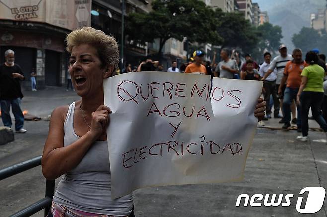 베네수엘라 카라카스에서 31일(현지시간) 한 반정부 시위 참가자가 '우리는 물과 전기를 원한다'는 구호가 적힌 종이를 들고 있다. © AFP=뉴스1