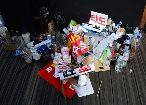 지난 27일 오후 서울 세종문화회관 앞에서 열린 자유한국당 집회에 사용된 각종 행사용품들이 바람에 날려 광화문 인근 카페 바닥에 나뒹굴고 있다.