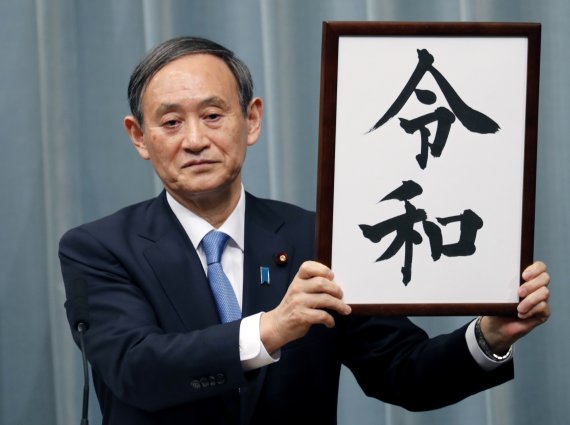 지난 4월 1일 일본 도쿄의 총리관저에서 스가 요시히데 일본 관방장관이 새 연호인 '레이와(令和)'가 적힌 액자를 들어 보이고 있다.AP연합뉴스