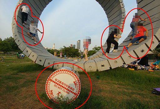 지난 8일 오후 서울 용산구 이촌 한강공원에 설치된 8m 스크룰 예술 작품에 20~30대로 보이는 성인들이 포즈를 취하며 올라가고 있다. 작품 주변에는 ‘타고 올라가지 마세요’라는 경고 표지판이 있지만 지켜지지 않고 있다.