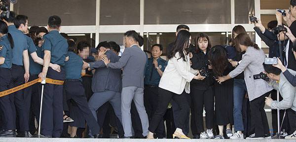 ⓒ시사IN 이명익 6월12일 고유정씨(오른쪽)가 제주지검에 송치될 때 고개를 숙이고 머리를 늘어뜨려 얼굴을 숨기자 피해자 유가족들(왼쪽)이 항의하고 있다.