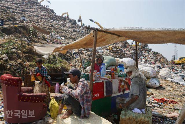 동남아 최대 쓰레기산인 인도네시아 반타르 그방 매립지 산중턱에 있는 식당에서 넝마주이들이 끼니를 때우며 쉬고 있다.