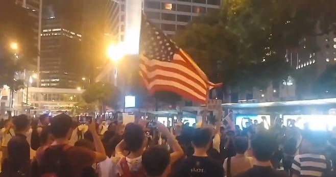 홍콩의 한 시위 참가자가 16일(현지시간) 지지를 호소하며 미국 성조기를 흔들고 있다. <트위터 영상 캡처>