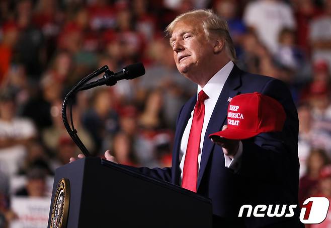 도널드 트럼프 미국 대통령이 15일(현지시간) 뉴햄프셔주 맨체스터 SNHU 아레나에서 열린 '미국을 계속 위대하게(Keep America Great)’ 선거유세 집회에서 자신을 상징하는 빨간 모자를 들어보이고 있다. © AFP=뉴스1