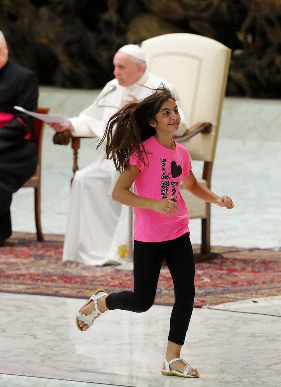 21일(현지시간) 바티칸에서 열린 일반알현에서 어린 소녀가 연단에 올라와 프란치스코 교황이 설교를 하는 동안 뛰어다니고 있다. [로이터=연합뉴스]