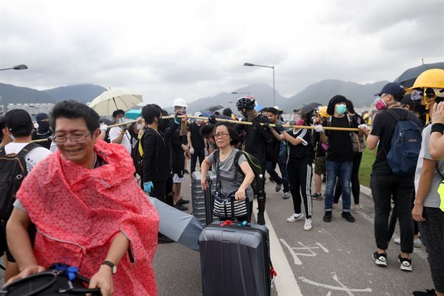 홍콩 시위대가 1일 공항으로 오가는 도로와 철도를 모두 봉쇄하면서 항공기 출발시간에 쫓긴 여행객들이 중간에 내려 캐리어를 끌고 가고 있다. EPA 연합뉴스