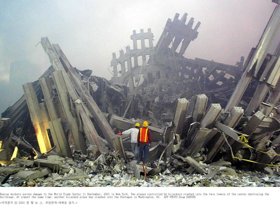 2001년 9·11테러로 무너진 미국 뉴욕의 세계무역센터 건물 잔해 속에서 구조대원들이 생존자를 수색하고 있다. [AFP=연합뉴스]