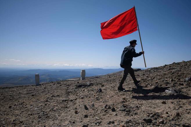 한 북한 학생이 붉은 깃발을 들고 백두산 정상으로 걸어가고 있다. [AP=연합뉴스]