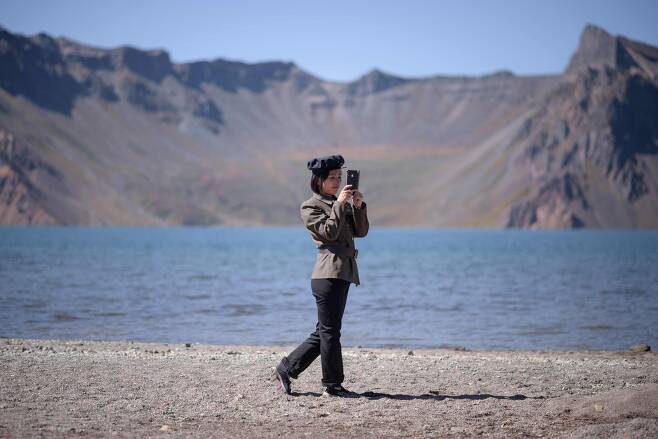 한 북한 학생이 스마트폰으로 백두산 천지를 카메라에 담고 있다. [AFP=연합뉴스]