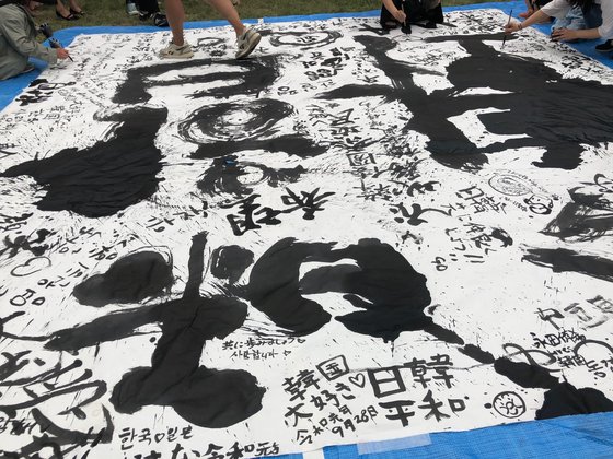 28일 일본 도쿄 히비야 공원에서 개막된 한일축제한마당을 찾은 참석자들이 대형 종이에 붓으로 각종 소감을 적었다. 서승욱 특파원