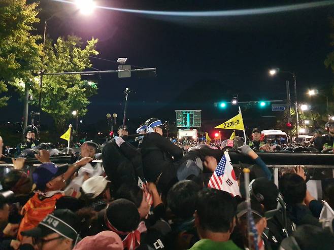 3일 저녁 한 60대 남성이 경찰이 설치한 바리케이드를 넘어가기 위해 바리케이드 위로 올라가고 있다. [사진=김민지 기자]