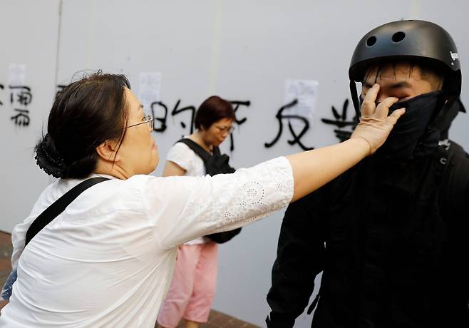 12일 한 여성이 시위대의 마스크를 벗기고 있다. [로이터=연합뉴스]
