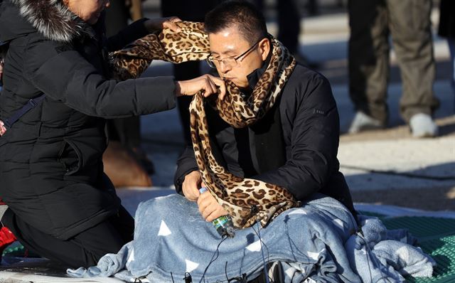 20일 오후 청와대 앞에서 한 시민이 단식투쟁을 시작한 황교안 한국당 대표에게 목도리를 둘러주고 있다. 연합뉴스.